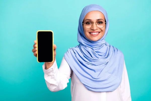 魅力的なかわいい若い女性の写真は、現代的なガジェットを保持するアラブのスカーフの眼鏡を着用空のスペース孤立ターコイズ色の背景 — ストック写真