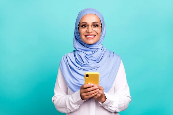 Foto de muito encantador jovem mulher usar óculos de lenço de cabeça árabe conversando gadget moderno isolado cor turquesa fundo — Fotografia de Stock