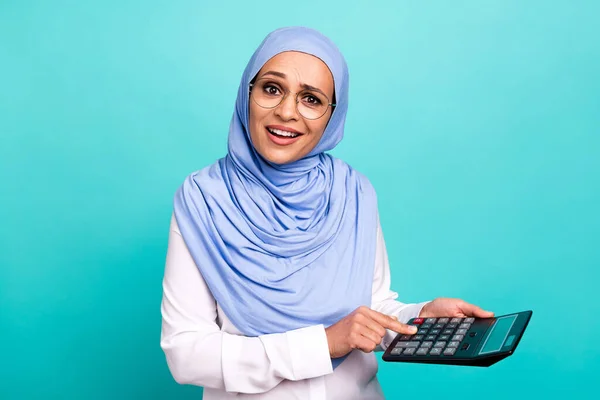 Fénykép zavarodott fiatal nő viselni arab fejkendő szemüveg számolás pénzügyek elszigetelt türkiz színes háttér — Stock Fotó