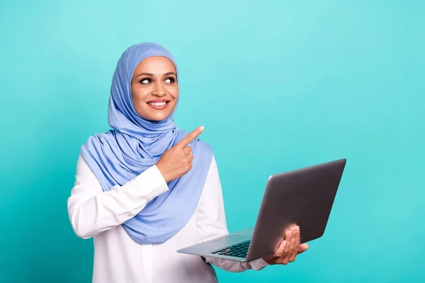 Foto di adorabile dolce giovane signora vestita hijab islamico sorridente che punta lo spazio vuoto dispositivo moderno isolato colore verde acqua sfondo — Foto Stock