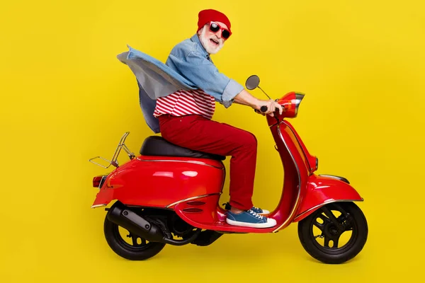 Profil sida visa porträtt av äldre pensionerad pensionär glad man ridning moped isolerad över ljusgul färg bakgrund — Stockfoto