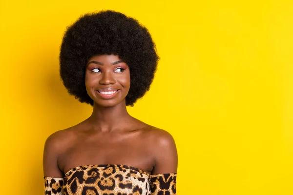 Foto de encantadora linda mujer de piel oscura vestida traje de leopardo buscando espacio vacío sonriendo aislado color amarillo fondo — Foto de Stock