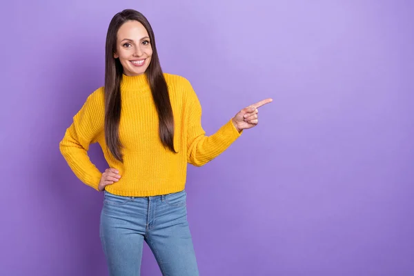 Foto de linda morena jovem senhora mostrar espaço vazio usar camisola amarela jeans isolado no fundo cor violeta — Fotografia de Stock