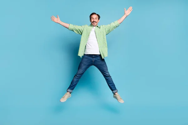 Ganzkörpergröße Ansicht von attraktiven fröhlichen freien Mann springen Spaß isoliert über helle blaue Farbe Hintergrund — Stockfoto