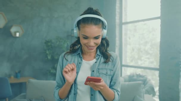 Zorgeloze grappige dame houden telefoon luisteren audio koptelefoon dansen naar huis — Stockvideo