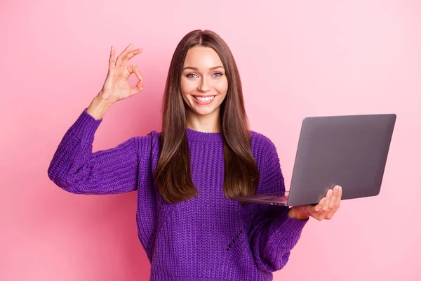 Zdjęcie ładnej pani trzymać laptopa palce pokazać dobrą pracę okey symbol nosić sweter izolowany na różowym tle kolor — Zdjęcie stockowe