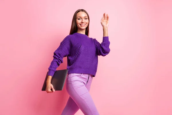 Foto de perfil de chica optimista sostener portátil onda mano desgaste pantalones de suéter lila aislado sobre fondo de color rosa —  Fotos de Stock
