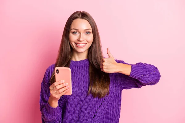 Fénykép elég vidám hölgy tartja telefon show hüvelykujj fel fogas mosoly viselet pulóver elszigetelt rózsaszín színű háttér — Stock Fotó