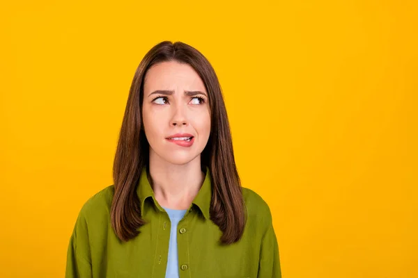 Foto von zweifelhaften traurige junge Dame tragen grünes Hemd beißende Lippe suchen leeren Raum isoliert gelbe Farbe Hintergrund — Stockfoto