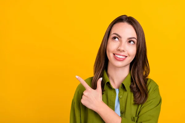 Foto de menina muito brilhante usar camisa verde olhando apontando o dedo vazio espaço sorrindo isolado cor amarela fundo — Fotografia de Stock