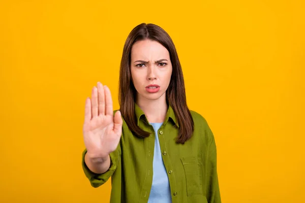 Zdjęcie nieszczęśliwy poważne młoda dama nosić zieloną koszulę pokazując gest zatrzymania palmy odizolowany żółty kolor tła — Zdjęcie stockowe