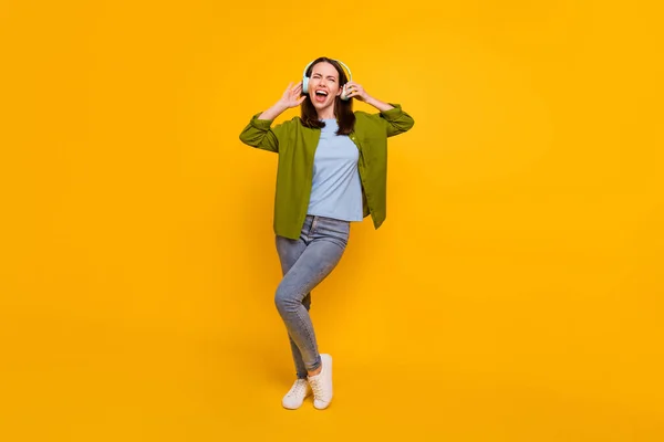 Foto de brilhante encantador jovem senhora usar fones de ouvido camisa verde sorrindo cantando dança isolado cor amarela fundo — Fotografia de Stock
