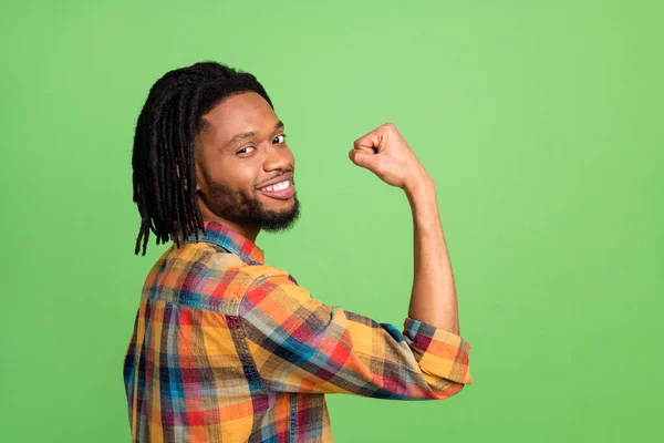 Фото смешного сильного темно-кожи мужчина носить клетчатую рубашку улыбаясь поднимающийся кулак изолированный зеленый цвет фона — стоковое фото