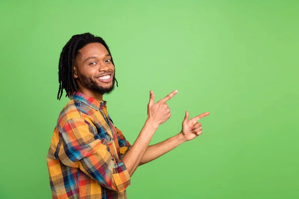 Photo of african guy direct finger empty space promote sale wear plaid shirt isolated green color background — Stock Photo, Image