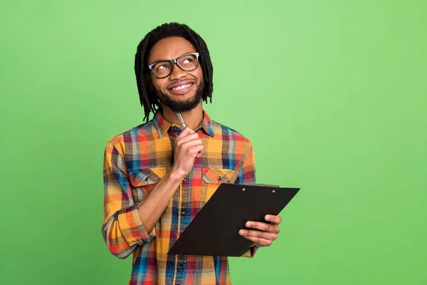 Zdjęcie młodego funky dobry nastrój afro facet wygląd copyspace myślenia trzymać organizator schowek izolowane na zielonym tle kolor — Zdjęcie stockowe
