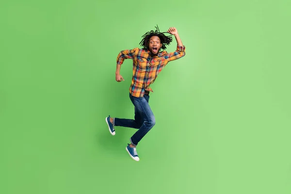 Foto de cara africano surpreso salto pressa corrida grito desgaste xadrez camisa jeans isolado cor verde fundo — Fotografia de Stock