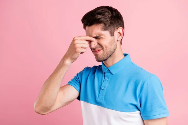 Portrét atraktivní depresivní brunetky chlap dotýkající se nosu pocit špatné křeče izolované přes růžové pastelové barvy pozadí — Stock fotografie