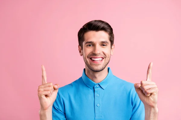 Foto van schattige brunet millennial guy wijzen op lege ruimte dragen blauw t-shirt geïsoleerd op roze kleur achtergrond — Stockfoto