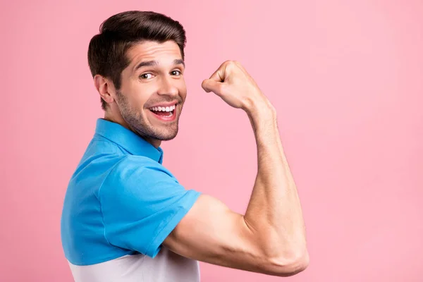 Foto de perfil do cara legal morena milenar mostrar músculo desgaste azul t-shirt isolado no fundo cor-de-rosa — Fotografia de Stock