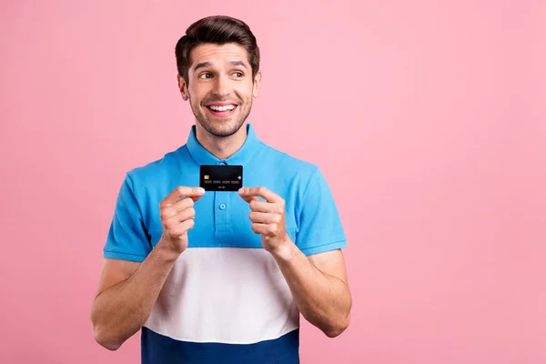 Foto van mooie brunet jonge man hold card look lege ruimte dragen blauw t-shirt geïsoleerd op roze kleur achtergrond — Stockfoto