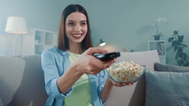 Lady sit divan néz TV képernyő használata távirányító Tartsa popcorn lemez a szobában — Stock videók