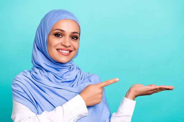 Foto de sonho bonito jovem vestido islâmico hijab sorrindo segurando braço apontando espaço vazio isolado cor teal fundo — Fotografia de Stock