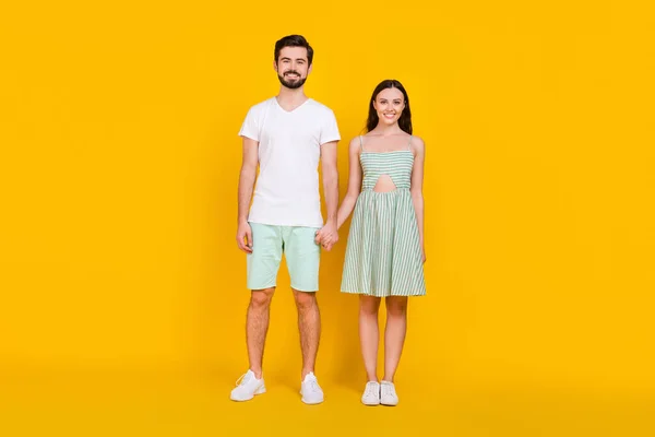 두 손을 잡고 있는 긍정적 인 매력적 인 커플의 사진, 평범 한 옷을 입고 있는 손에 노란 색 배경을 가진 운동화 — 스톡 사진