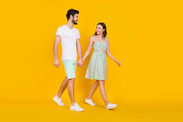 Fotografie okouzlující pár držet ruce těšit bezstarostné kroky nosit ležérní oblečení izolované žluté barvy pozadí — Stock fotografie