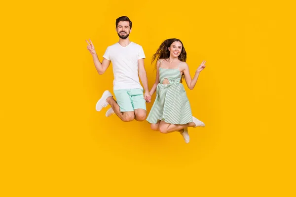 Foto de pareja amigable salto de la mano disfrutar de espectáculo de vuelo v-signo de desgaste traje casual aislado de color amarillo de fondo — Foto de Stock