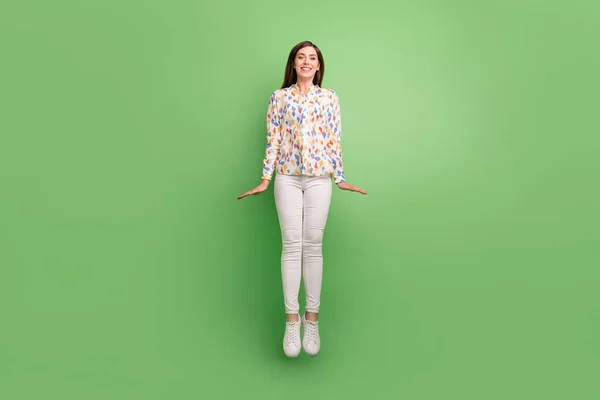 Full size foto van funky brunette kapsel millennial dame springen dragen blouse broek sneakers geïsoleerd op groene achtergrond — Stockfoto