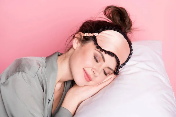 Portret dziewczyny w masce piżamy śpiącej na białej miękkiej poduszce odizolowanej na pastelowym różowym tle — Zdjęcie stockowe
