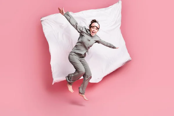 Volledige lengte lichaamsgrootte uitzicht van vrij gek vrolijk meisje springen op bed met plezier geïsoleerd over roze pastel kleur achtergrond — Stockfoto