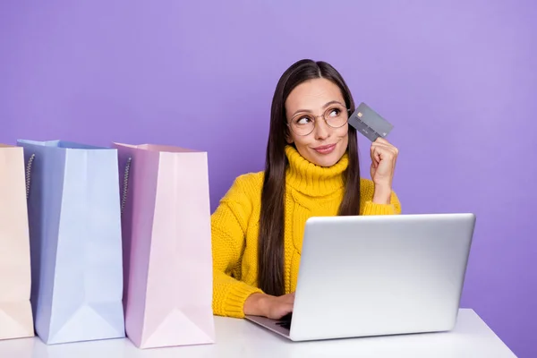 Foto av förundrad kvinna ser copyspace tänkande shopping online använda plastkort isolerad på violett färg bakgrund — Stockfoto