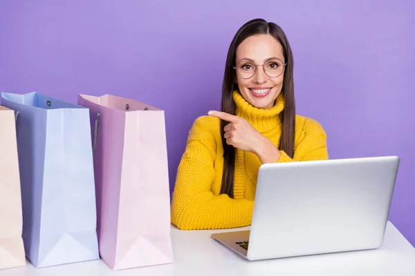 Foto av leende flicka i casual stickad tröja annons rekommenderar online shopping isolerad på violett färg bakgrund — Stockfoto