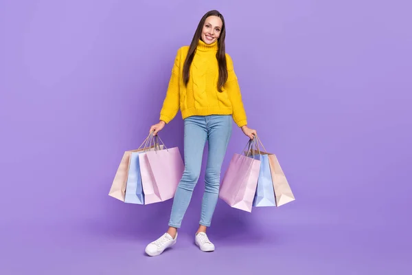 Фотография в натуральную величину довольно зрелой женщины, позирующей с сумками для покупок любовника, изолированного на фиолетовом фоне — стоковое фото