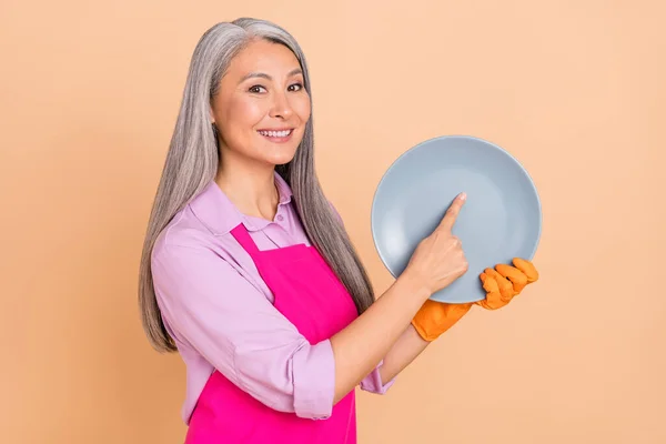 Portret van aantrekkelijke vrolijke grijs-harige vrouw afvegen plaat perfect nette service geïsoleerd over beige pastel kleur achtergrond — Stockfoto