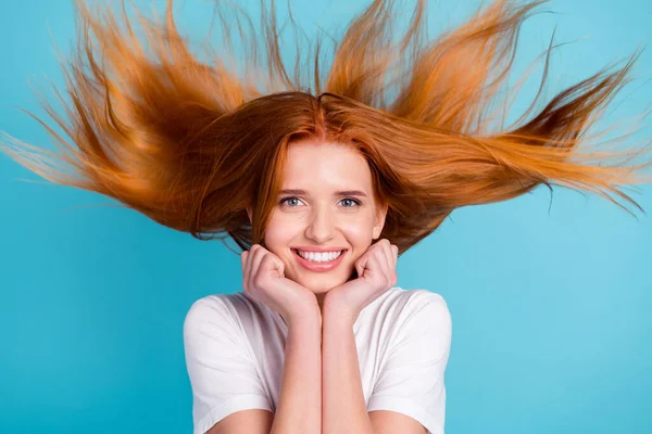 Zdjęcie młodej dziewczyny szczęśliwy pozytywny uśmiech ręce dotyk podbródek wiatr cios rude włosy cieszyć się nową odżywkę izolowane nad niebieskim tle kolor — Zdjęcie stockowe