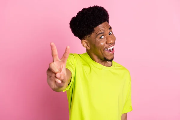 Foto de encantador joven piel oscura feliz hombre positivo mostrar v-signo de desgaste camiseta de cal aislada sobre fondo de color rosa —  Fotos de Stock