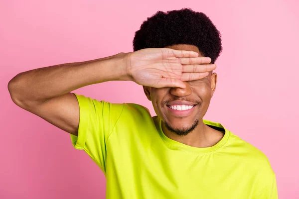 Foto van positieve jonge donkere huid man houden hand cover ogen dragen limoen t-shirt geïsoleerd op pastel roze kleur achtergrond — Stockfoto
