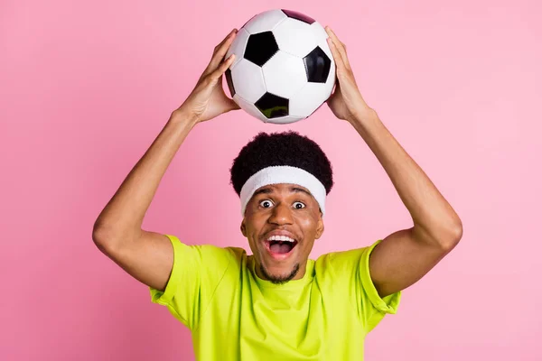 Портрет привлекательного веселого парня, бросающего мяч, играющего футбольное хобби на розовом пастельном фоне — стоковое фото