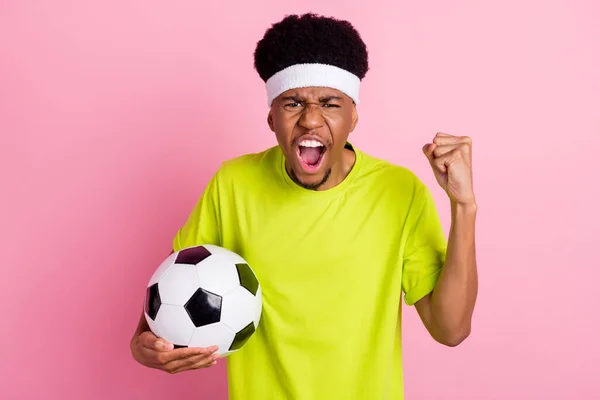 Фото молодого взволнованного африканца парень болельщик матч провести футбольный мяч изолированы на розовом фоне — стоковое фото