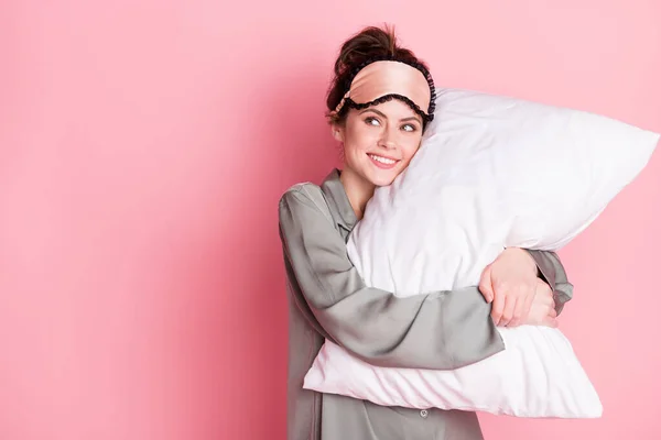 Portret van aantrekkelijke vrolijke dromerige meisje dragen pyjama knuffelen kussen kopiëren ruimte geïsoleerd over roze pastel kleur achtergrond — Stockfoto