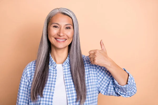 Fénykép magabiztos hangulatos hölgy nyugdíjas öltözött kockás ing mutatja hüvelykujj fel mosolygós elszigetelt bézs színű háttér — Stock Fotó