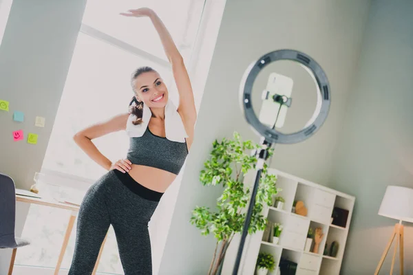 Foto de la niña flexible de ensueño vestido traje deportivo estiramiento grabación video sonriendo en el interior de la casa de casa —  Fotos de Stock
