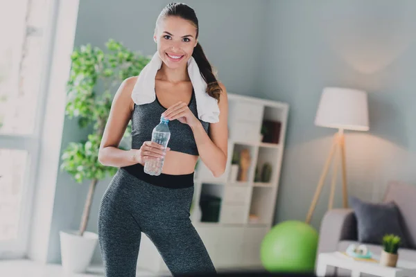 Foto von süßen müde Dame tragen Sport-Outfit lächelnd Abschluss Ausbildung Trinkwasser in Innenräumen Haus — Stockfoto