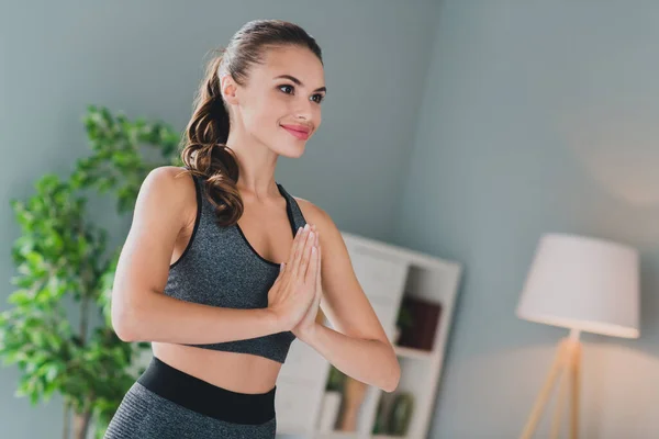 Foto de dulce adorable chica vestida traje deportivo brazos manos juntas practicando yoga sonriendo en el interior de la casa de casa —  Fotos de Stock