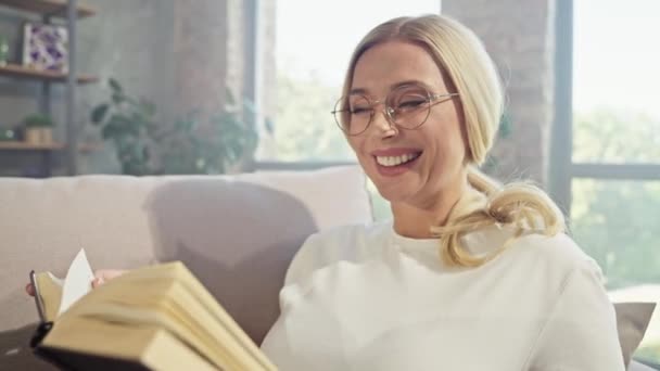 Positiv schöne verträumte Dame sitzen bequeme Couch lesen Roman Buch — Stockvideo