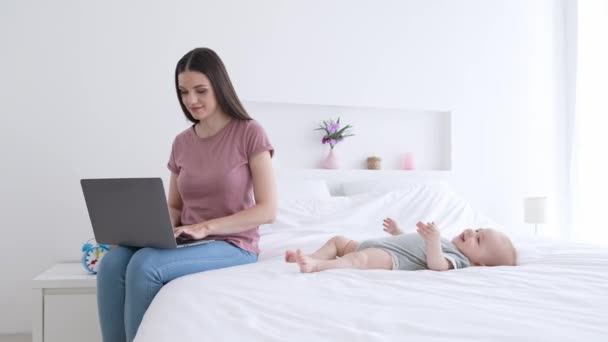 엄마 프리랜서 가 집에서 인터넷 채팅으로 아기 침대에 누워 있는 아기의 가족을 돌봐 주는 일을 한다 — 비디오