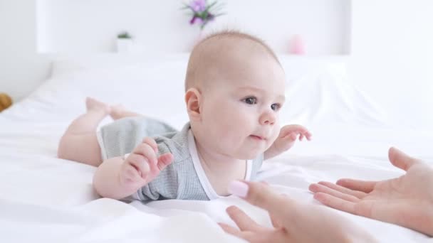 Carino bambino ragazzo vuole strisciare letto mamma mostrando mani palme al chiuso — Video Stock