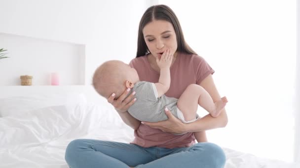Milující matka sedět postel hrát batole chlapec dítě líbání tvář grimasa uvnitř — Stock video